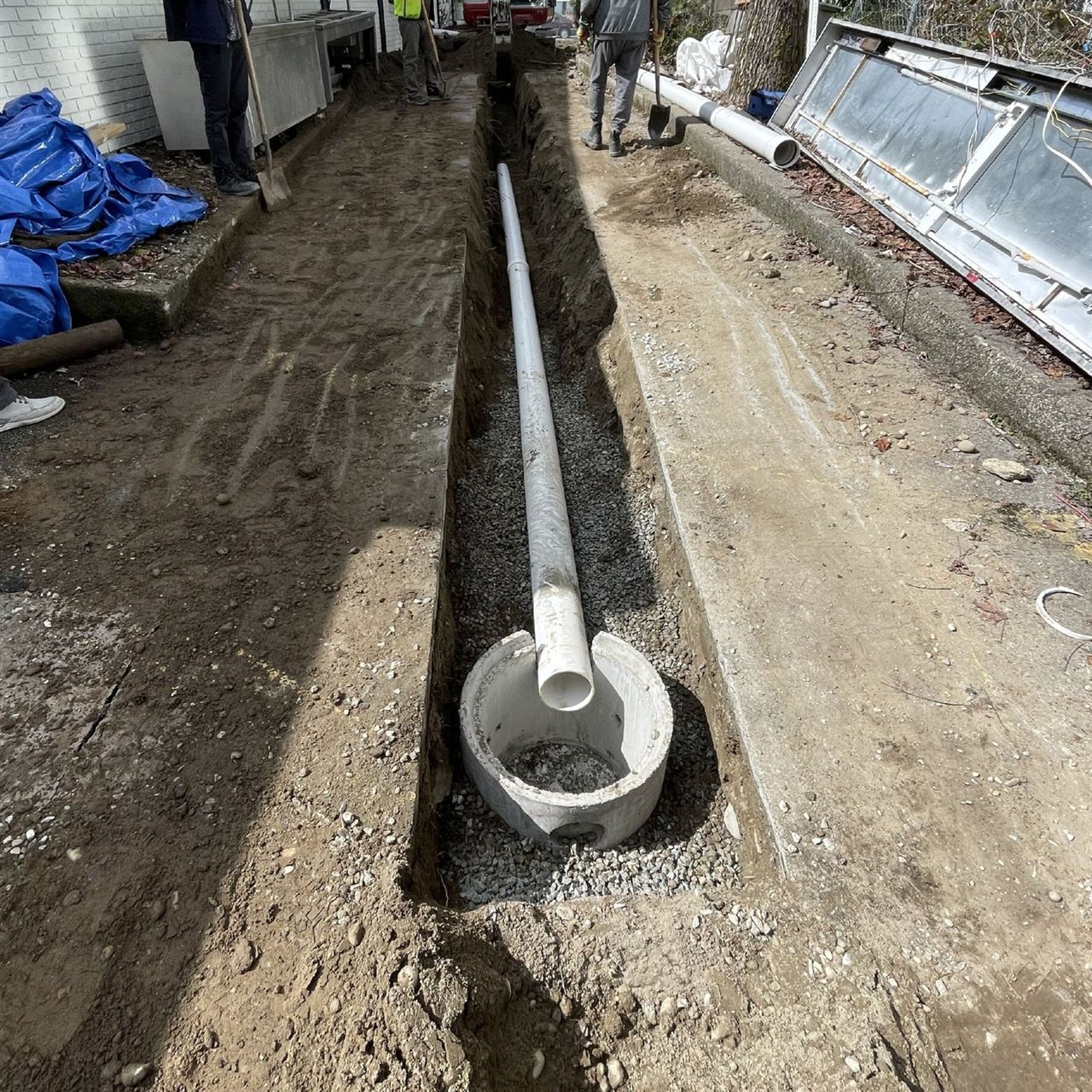 Open trench with pipe running to a concrete catch basin