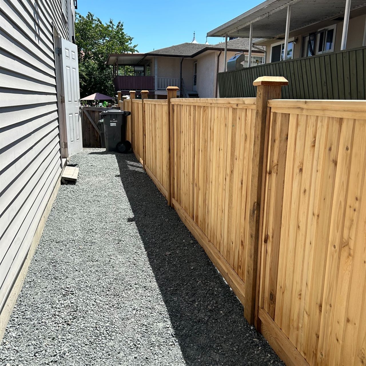 Cedar privacy fence along a gravel side yard