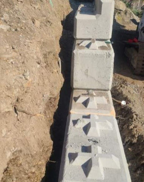 Concrete lock block wall install — large lock-blocks set into a trench